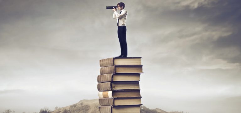 Pessoa com luneta no alto de uma pilha de livros olha o horizonte