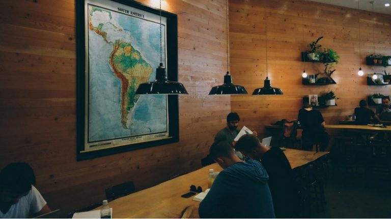 Pessoas trabalham numa mesa compartilhada de um espaço de coworking